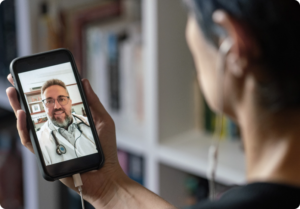 paciente com celular fazendo teleconsulta com médico na tela