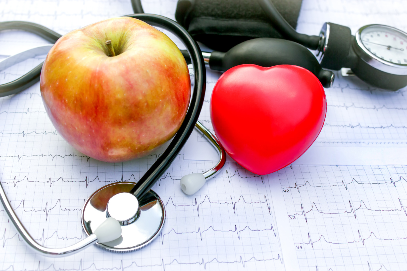 Medicina preventiva: imagem de estetoscópio e exame ECG ao lado de uma maçã, sugerindo hábitos saudáveis