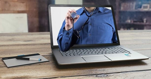 Princípios da telessaúde: médico com camisa azul dentro de um computador com um estetoscópio