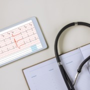 tablet con informe de electrocardiograma y aparatos médicos