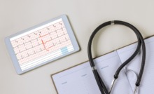 tablet con informe de electrocardiograma y aparatos médicos