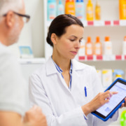 farmaceutica atendendo cliente na farmácia mostrando uma receita digital com através de um tablet