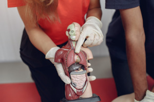 pequeno boneco com área frontal aberta e mulher indicando com dedo área do coração