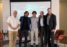 palestrantes em pé pousam para foto em palco de apresentação