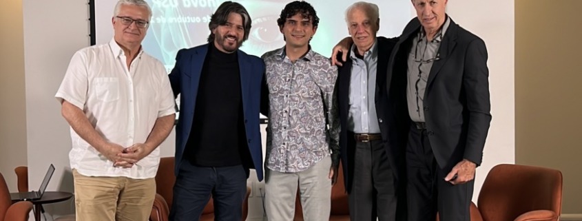 palestrantes em pé pousam para foto em palco de apresentação