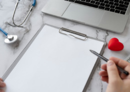 prancheta com receita médica em branco, na mesa ao lado de um notebook