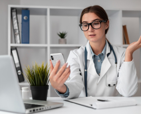 médica em consultório com celular na mão falando com paciente