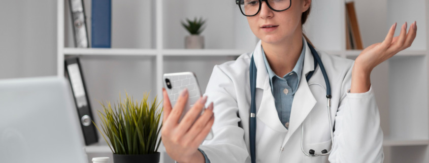 médica em consultório com celular na mão falando com paciente