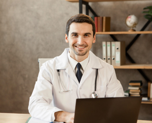 médico em consultório sorrindo na mesa de atendimento