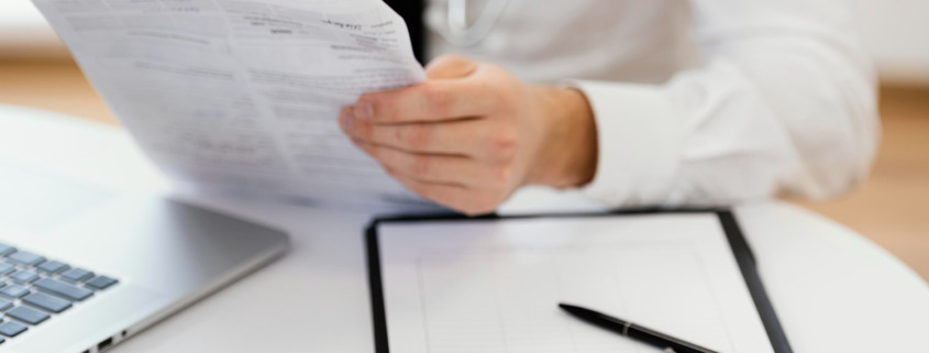 médico em consultório segurando um documento com uma prancheta na mesa