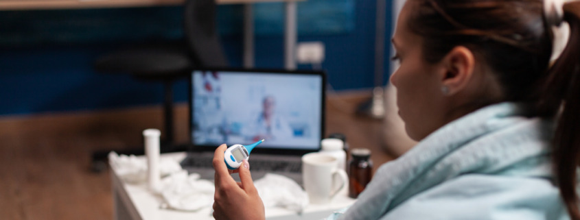 mulher gripada no sofá com consulta de telemedicina em tablet