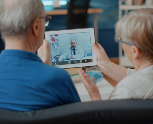 casal de idosos conversando com médico por tablet