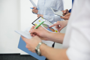 várias mãos de pessoas com jaleco branco manuseando tablet e papeis