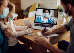 pais com filha em consulta por telemedicina via notebook