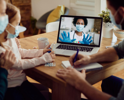 pais com filha em consulta por telemedicina via notebook