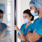 dois enfermeiros com uniforme azul reunidos e apontando tela