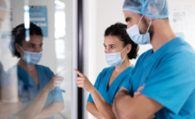 dois enfermeiros com uniforme azul reunidos e apontando tela