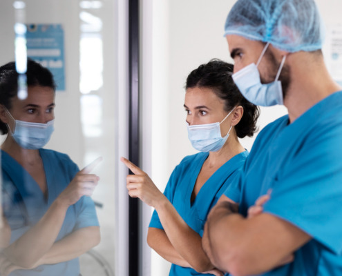 dois enfermeiros com uniforme azul reunidos e apontando tela
