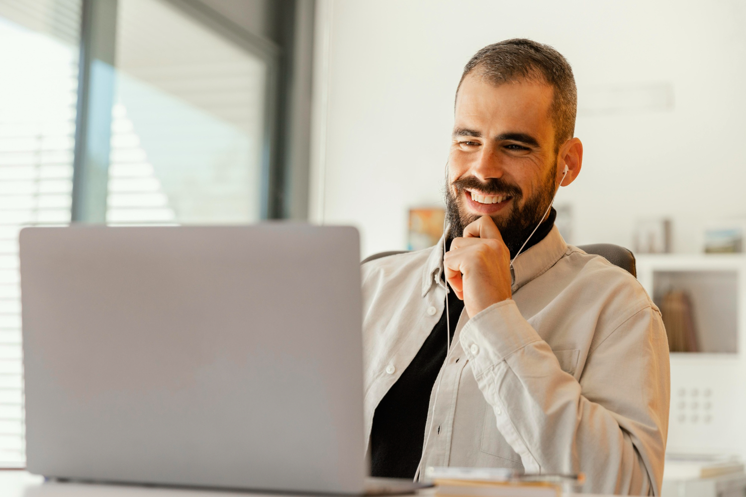 homem de barba sorrindo e olhando para notebook