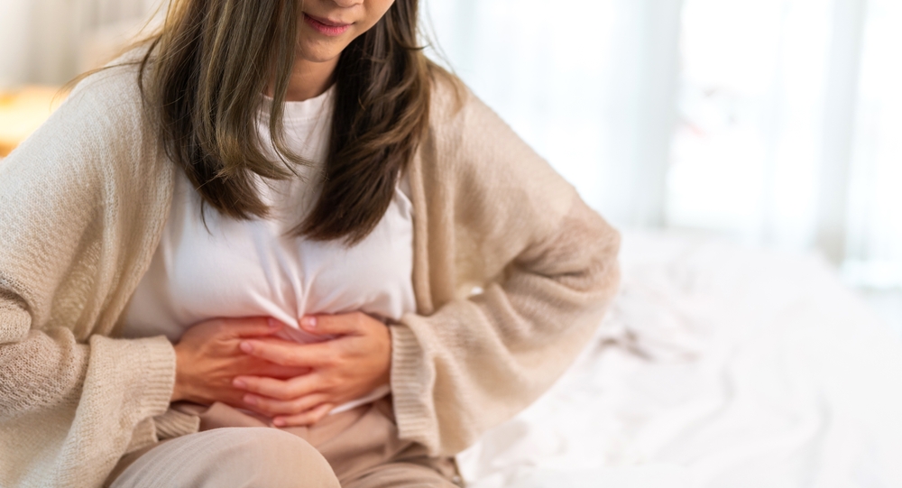 mulher com mão na barriga e semblante de dor