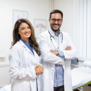 casal de médicos sorrindo e braços cruzados em ambiente hospitalar