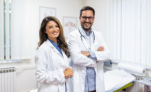 casal de médicos sorrindo e braços cruzados em ambiente hospitalar