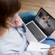 mulher sentada com notebook no colo, em chamada com outra mulher na tela
