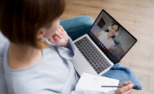 mulher sentada com notebook no colo, em chamada com outra mulher na tela