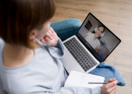 mulher sentada com notebook no colo, em chamada com outra mulher na tela