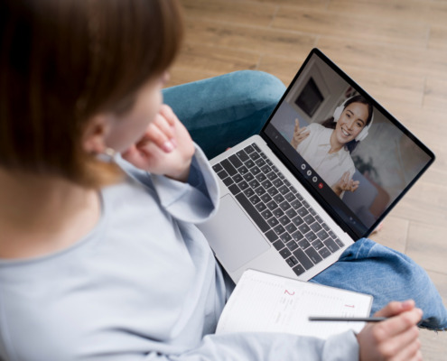 mulher sentada com notebook no colo, em chamada com outra mulher na tela