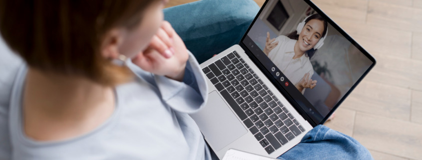 mulher sentada com notebook no colo, em chamada com outra mulher na tela