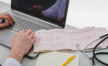 notebook na bancada com exame de eletrocardiograma ao lado