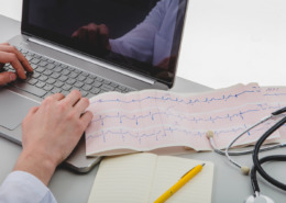 notebook na bancada com exame de eletrocardiograma ao lado