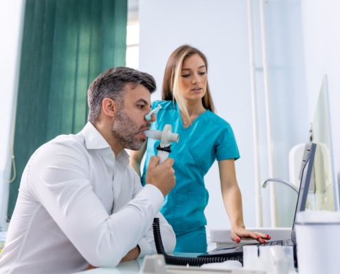 homem fazendo espirometria com enfermeira ao lado