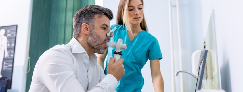 homem fazendo espirometria com enfermeira ao lado