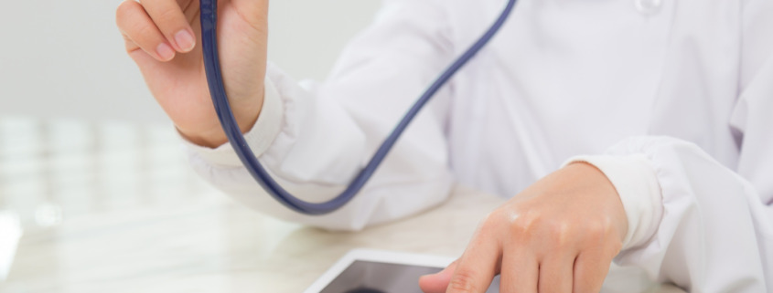 médico segura estetoscópio com uma mão e aponta o dedo em um tablet