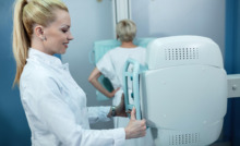 médica em pé realizando exame de mamografia em paciente ao fundo