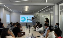 CEO da Portal Telemedicina lidera reunião apontando na tela dos dados com expectadores na sala