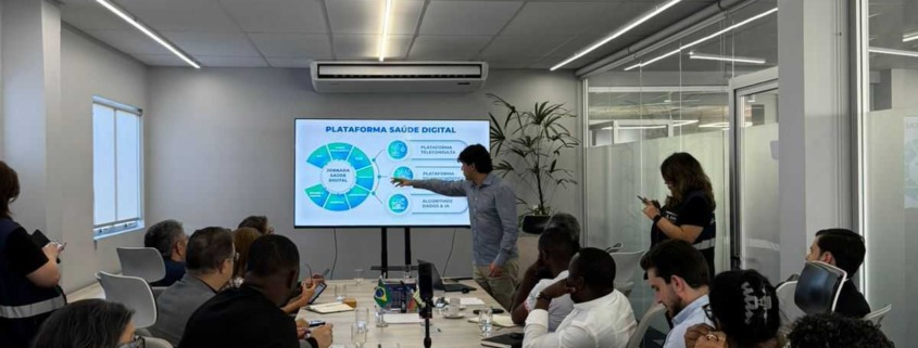 CEO da Portal Telemedicina lidera reunião apontando na tela dos dados com expectadores na sala
