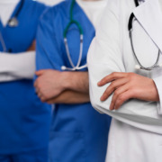 Corpo de três médicos sendo um com jaleco branco e dois com jalecos azuis