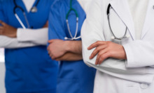 Corpo de três médicos sendo um com jaleco branco e dois com jalecos azuis