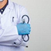 braço de médico com jaleco e segurando estetoscópio no braço