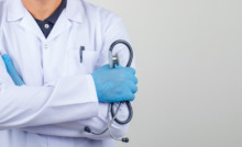 braço de médico com jaleco e segurando estetoscópio no braço
