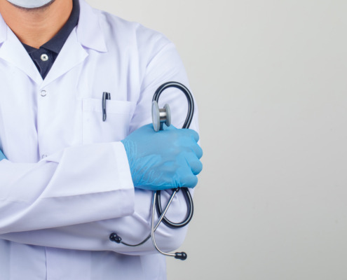 braço de médico com jaleco e segurando estetoscópio no braço