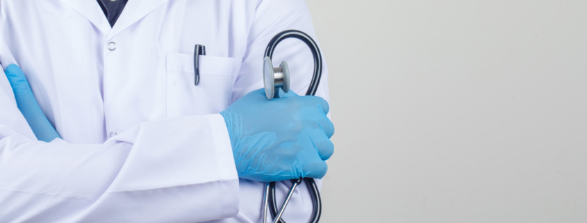 braço de médico com jaleco e segurando estetoscópio no braço