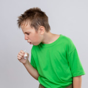 criança com camiseta verde e tossindo