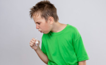 criança com camiseta verde e tossindo