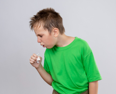 criança com camiseta verde e tossindo
