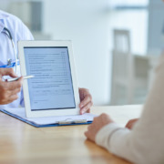 médico no consultório mostrando tela do tablet com formulário para paciente