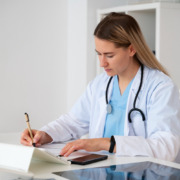 mulher médica sentada no consultório anotando em papel